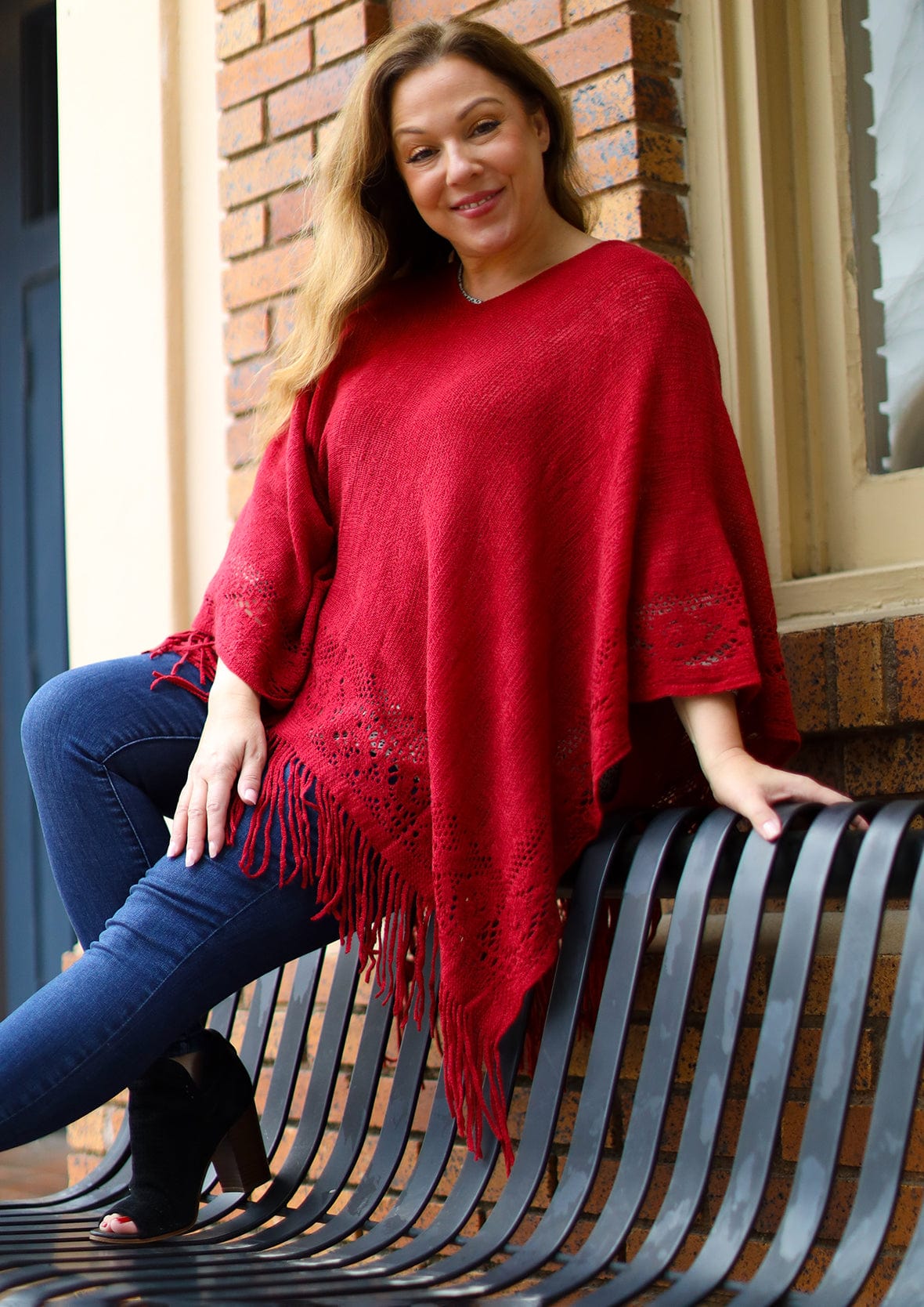 lady wearing fringe detailed knitted red poncho #color_Candy red knit